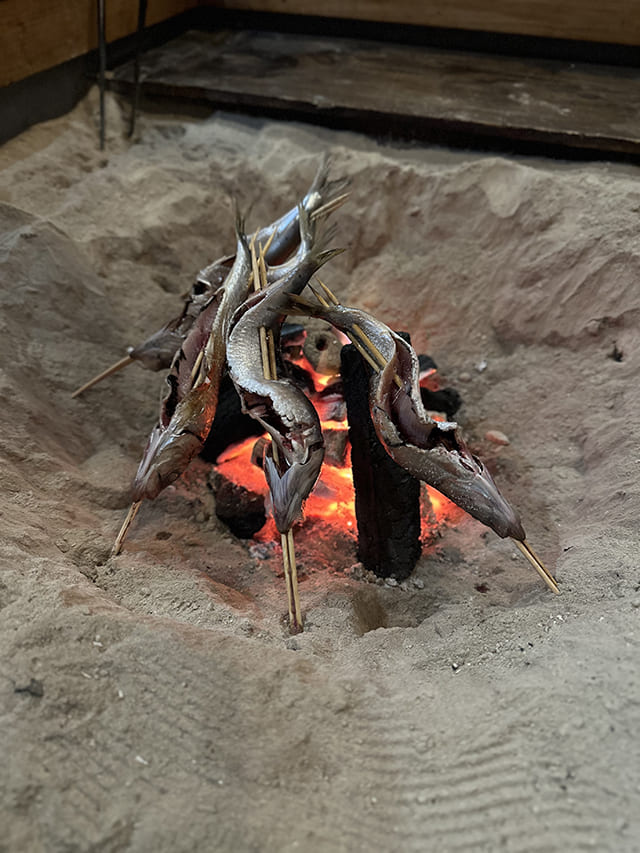囲炉裏で魚を焼いている様子